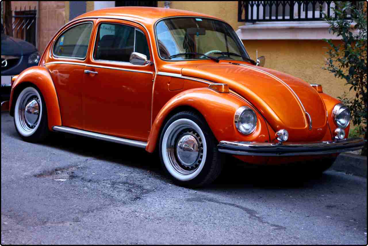 Orange vintage hatchback car parked on a street.